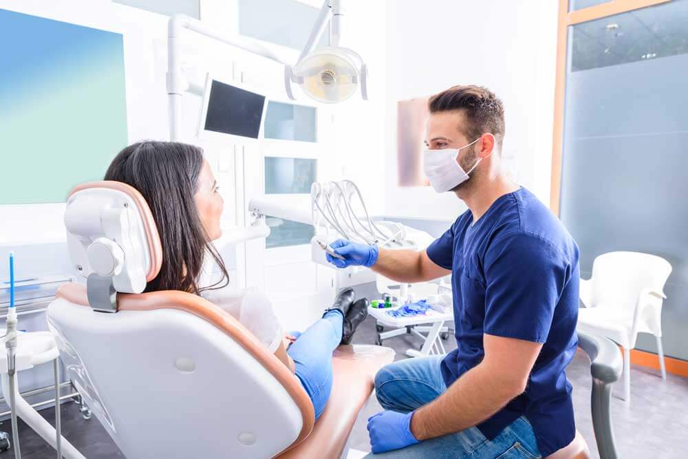 A young Dentist treating a female Patient in the dental studio