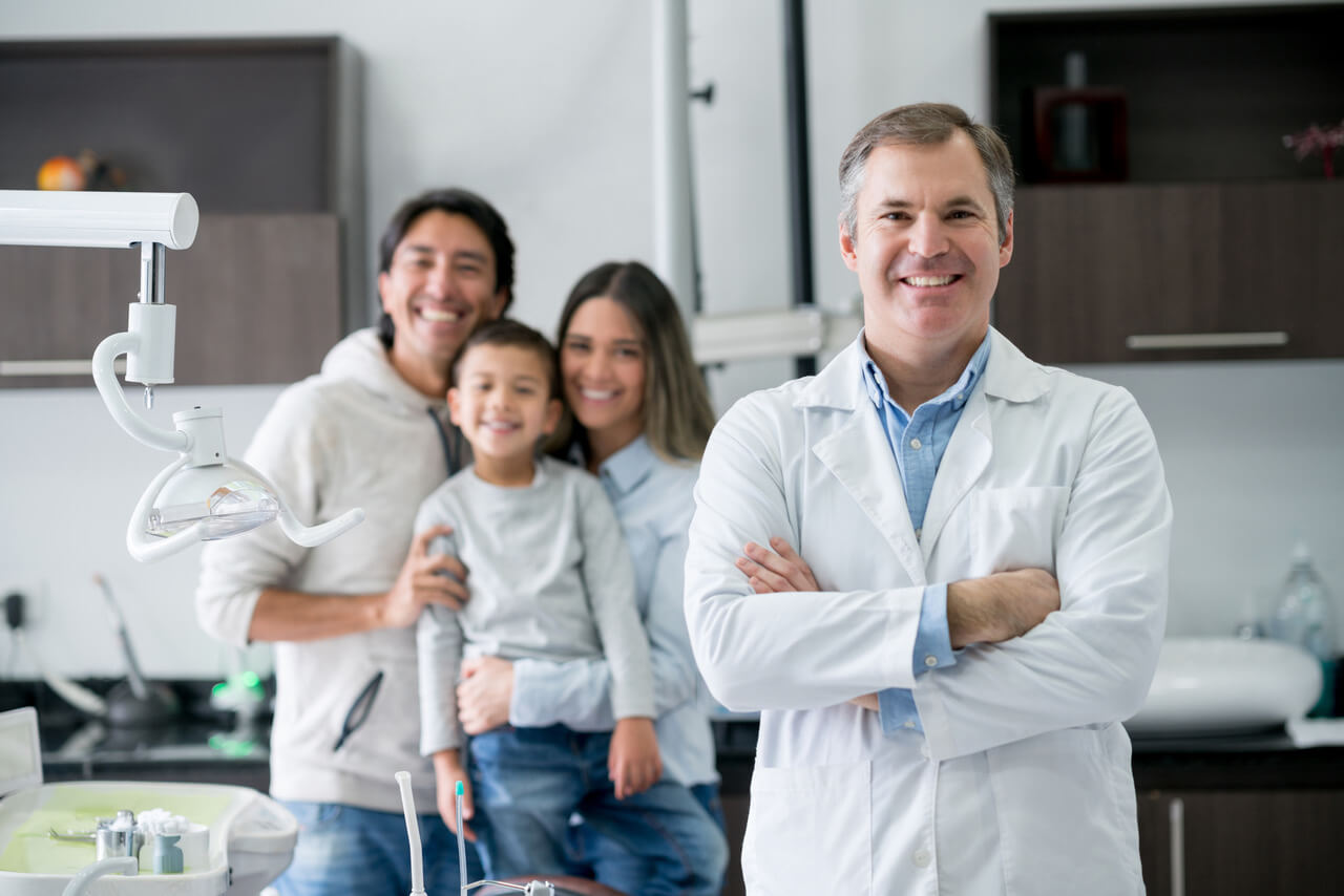 Dentist at the office looking very happy with a family at the background